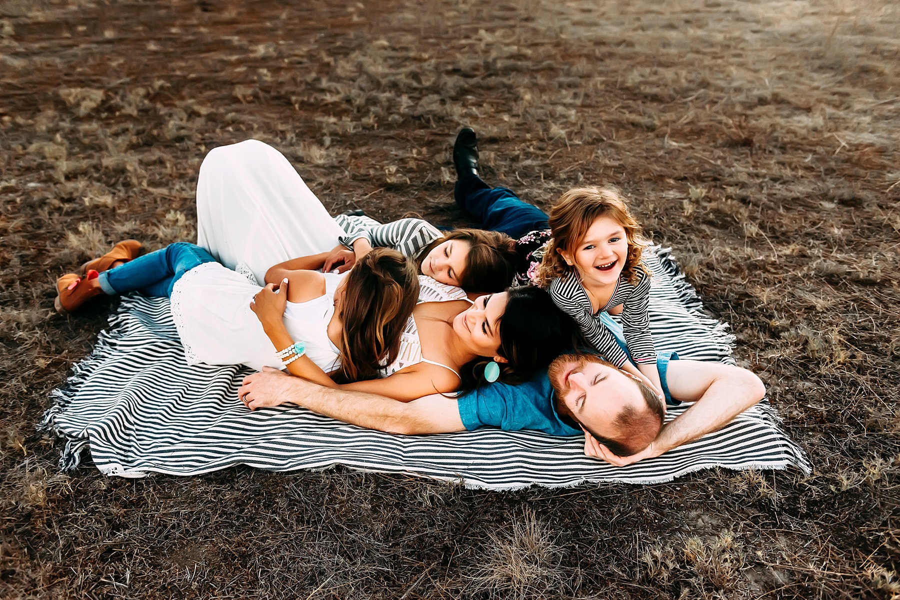 family pictures in a field laying down pose