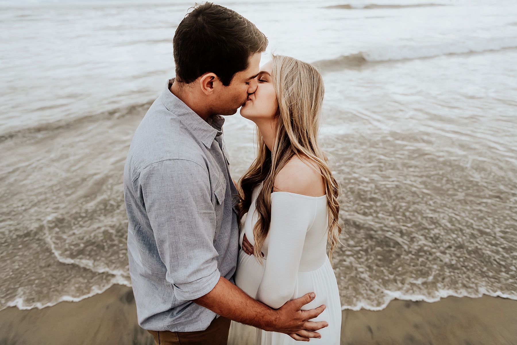 beach maternity photos couple kissing
