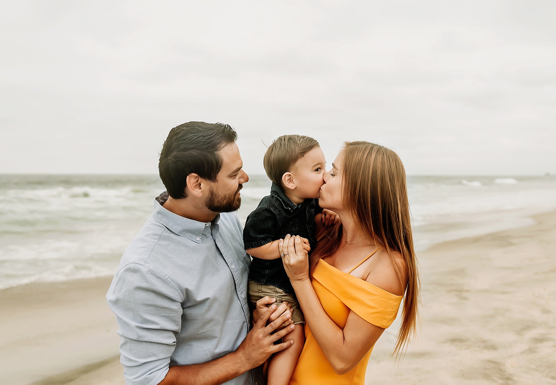 family of three beach pictures son kissing mom