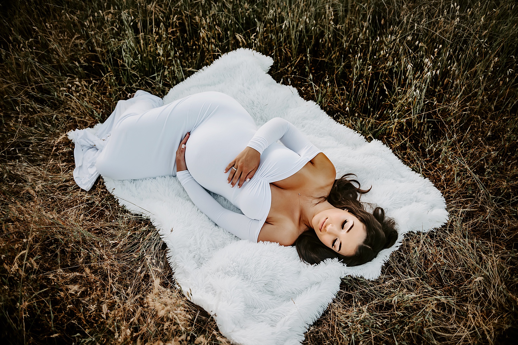 sunset field maternity session laying on white blanket